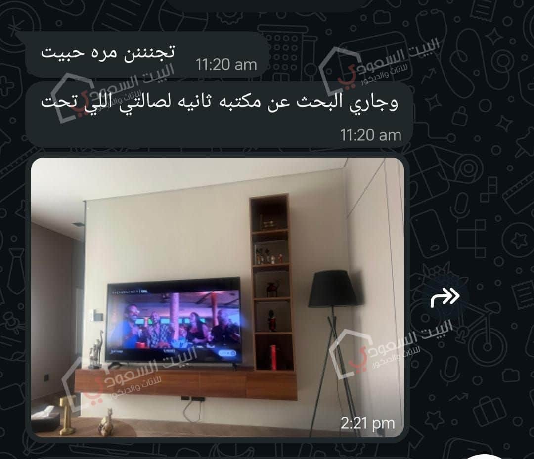 طاولة تلفزيون جدارية لون بني مع رفوف جانبية وإضاءة لاسلكية داخل منزل أحد عملاء البيت السعودي